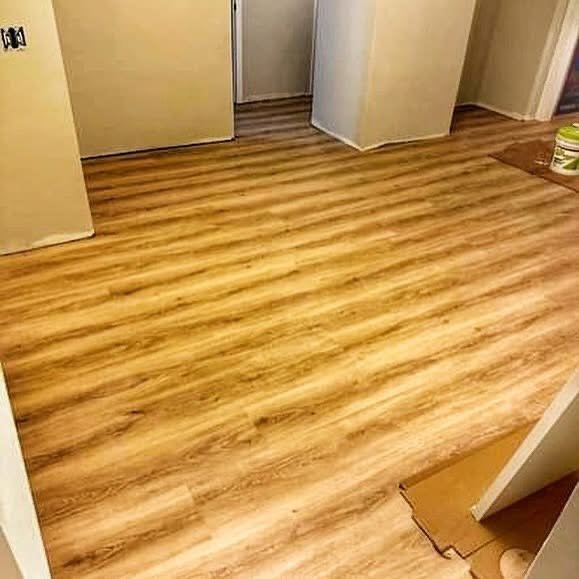 Kitchen with warm-toned vinyl plank flooring and painted cabinets